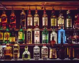 Rzędy butelek alkoholi, w tym whisky, ginu i likierów, na półkach baru.