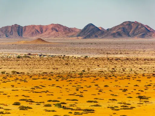 Krajobraz Namibii: pustynne równiny, góry i mała osada.