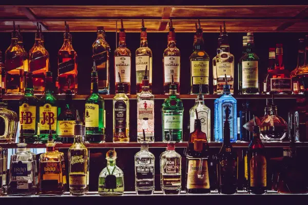 Rzędy butelek alkoholi, w tym whisky, ginu i likierów, na półkach baru.